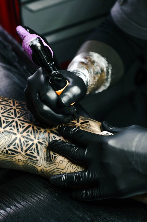 Foto di qualcuno che sta tatuando una parte del corpo di un'altra persona