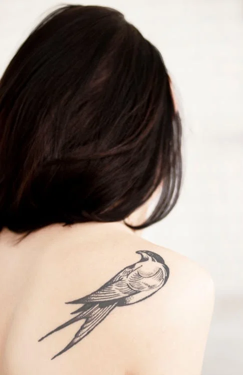 Foto di una donna di schiena che ha un uccello tatuato