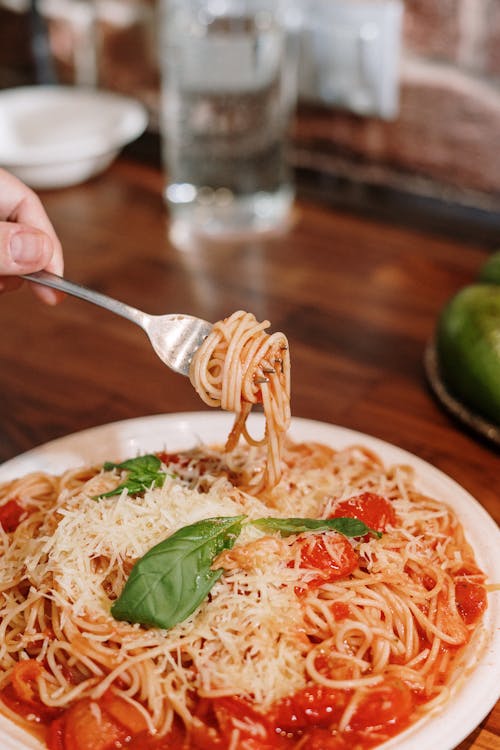 Piatto di spaghetti al pomodoro con del parmigiano e del basilico