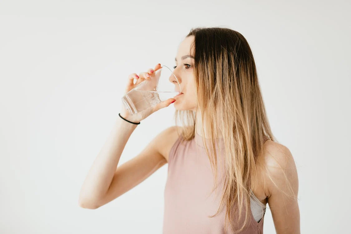 Foto di una donna che sta bevendo acqua da un bicchiere