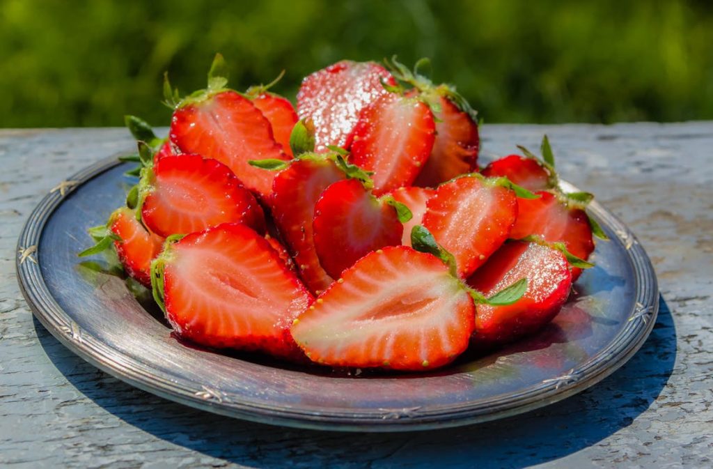 Foto di un piatto pieno di fragole tagliate a metà