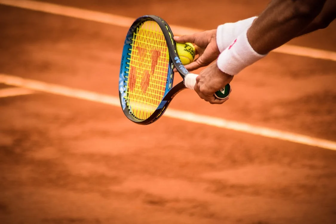 Foto di una racchetta da tennis tenuta in mano da una persona che sta per tirare