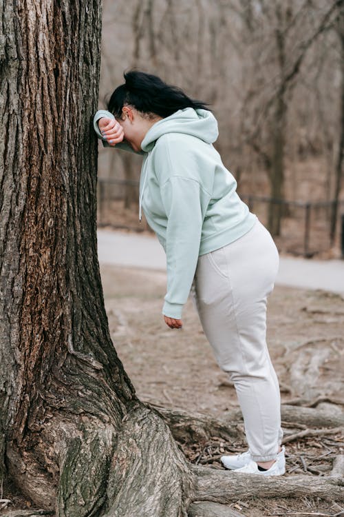Foto di una donna poggiata con il braccio su un albero