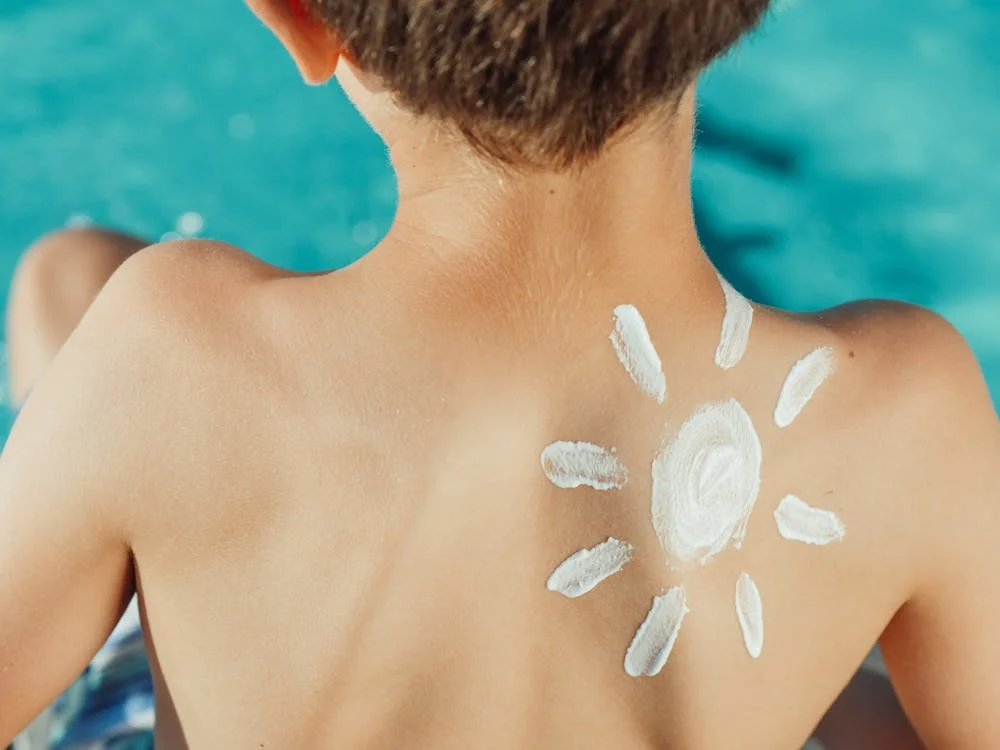 Foto di un bambino di spalle con dell'SPF messa a forma di sole
