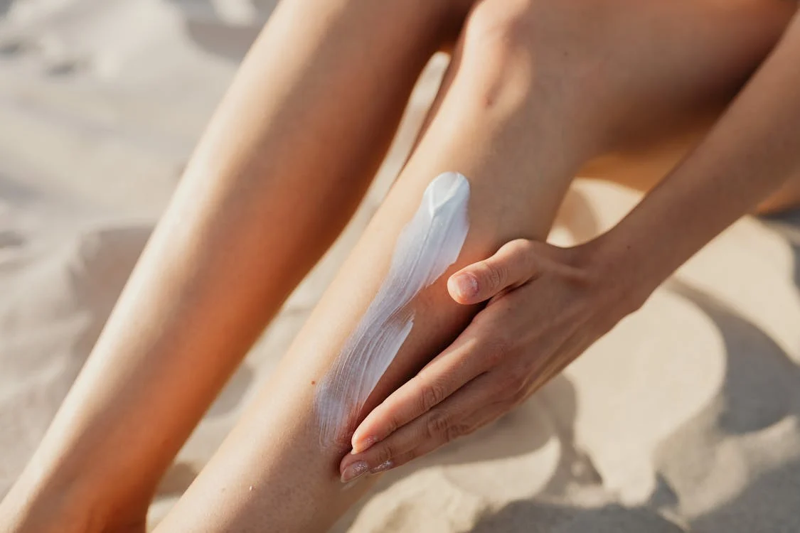 Foto di una donna che si sta spalmando la protezione solare sulle gambe